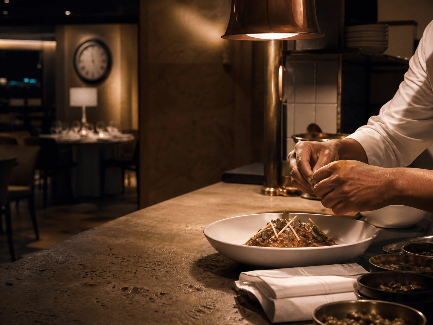 A chef finishing a late-night dish at the hotel kitchen pass